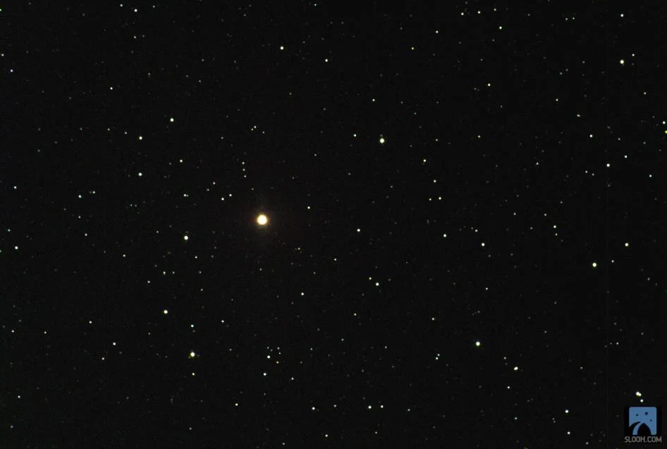 Campo estelar con una estrella anaranjada brillante en el centro